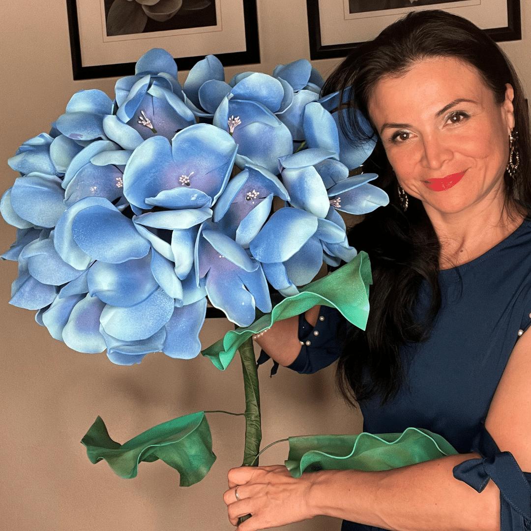 Woman holding completed giant blue-purple hydrangea foam flower from DIY craft kit by Amazing Giant Flowers