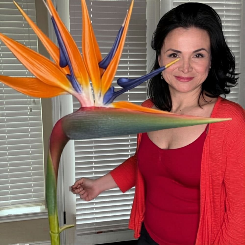 Woman displaying completed giant bird of paradise foam flower in vibrant orange and blue tropical colors