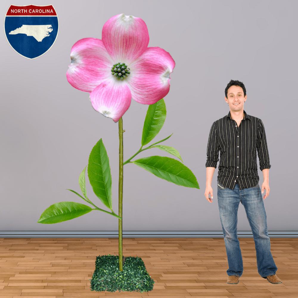 Man standing next to giant pink dogwood flower representing North Carolina state flower for display