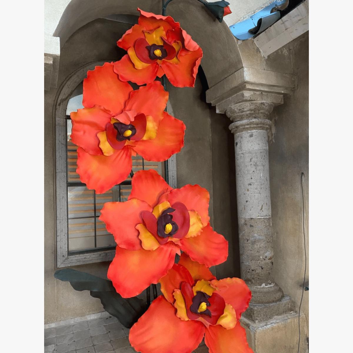 10-foot tall orange orchid arrangement with cascading blooms against stone wall for luxury event installation